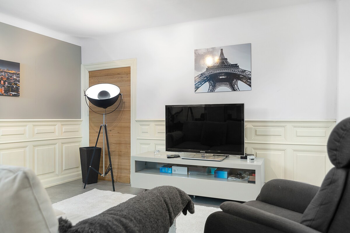 غرفة معيشة بها تلفزيون وأريكة بثلاثة مقاعد ومقعد. تتحول الأريكة إلى سرير 160 × 200. 