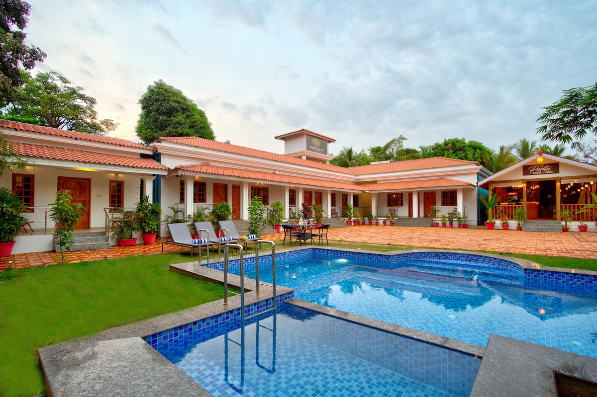 A spacious outdoor area features a shimmering blue pool surrounded by manicured grass and potted plants. The single-story structure, with a red-tiled roof, is visible in the background, complemented by large windows that allow natural light to enter.