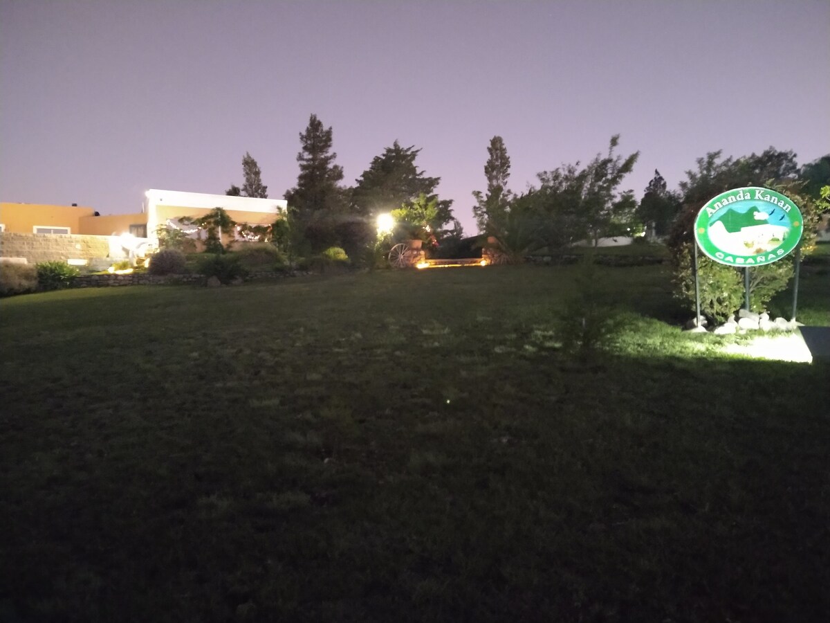 The well-maintained grounds feature lush greenery under evening lights, creating a serene environment. A prominent sign indicates the location, and the surrounding trees add a natural element to the setting, enhancing the tranquil atmosphere of the area.