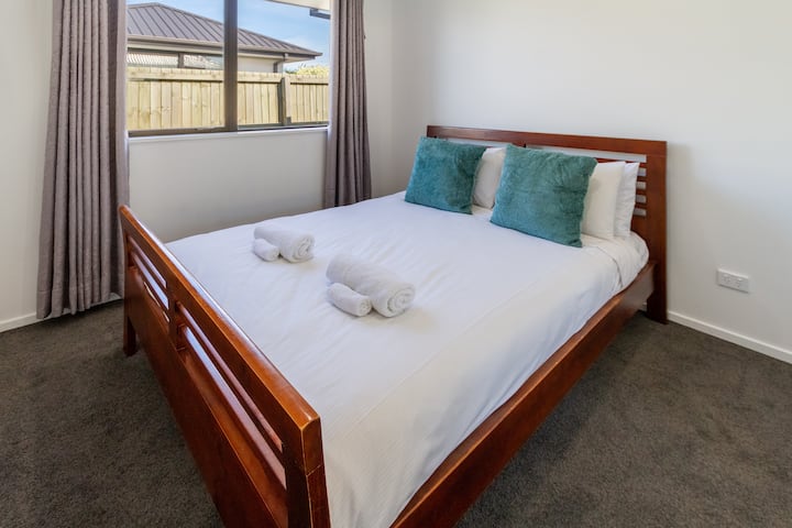 Priestranná spálňa s manželskou posteľou a dekoratívnymi vankúšmi