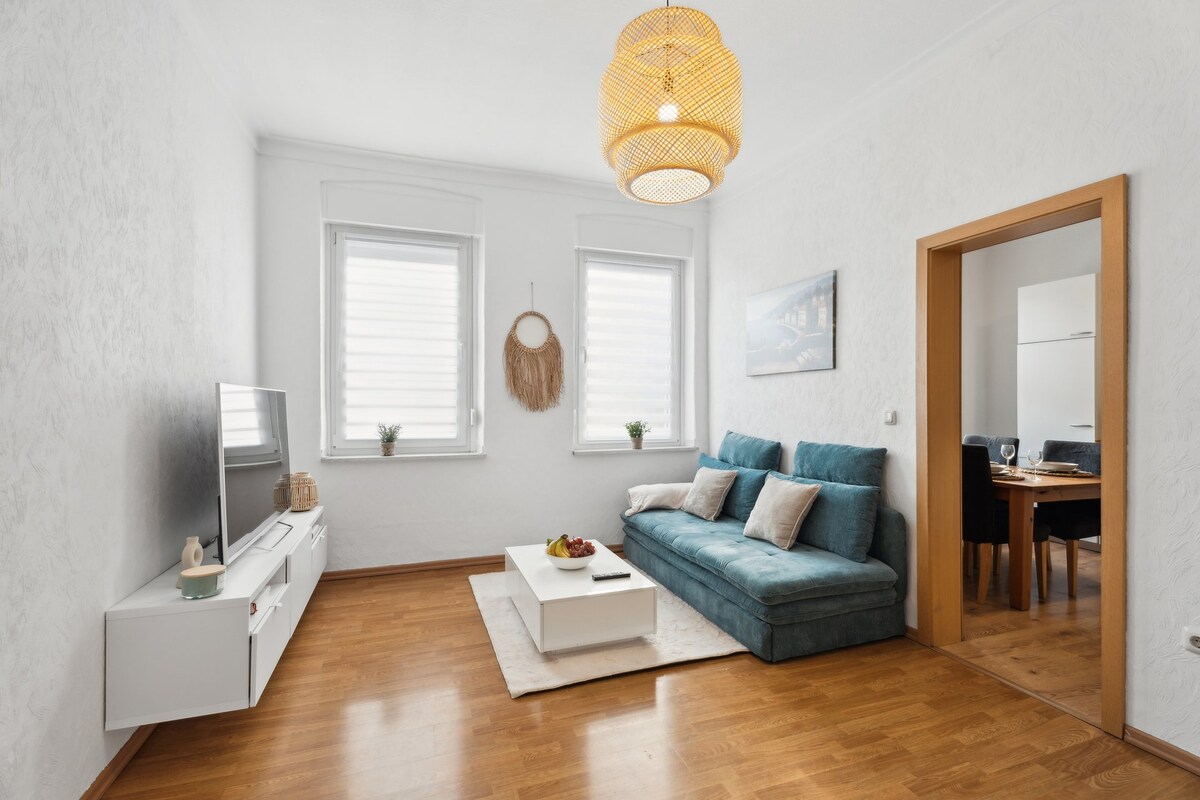 Dhomë ndenjjeje me divan të rehatshëm, televizor inteligjent 55 "dhe tavolinë kafeje