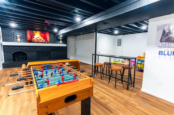 ห้องเล่นเกมกว้างขวางพร้อมโต๊ะฟุตบอลคลาสสิก ที่นั่งบาร์ และผังแบบเปิดโล่ง เหมาะสำหรับความสนุกสนานเป็นกลุ่มและการแข่งขันอย่างเป็นกันเอง