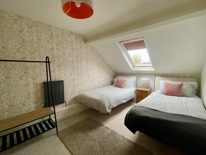 Cosy twin bedroom with en-suite. 'Squirrel and sunflower' wallpaper by artist Mark Hearld (in case you wondered)