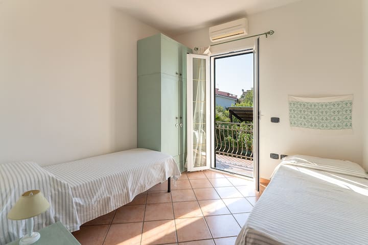 Dormitorio 3 con dos camas individuales, zona de aire acondicionado y balcón con vistas al campo.