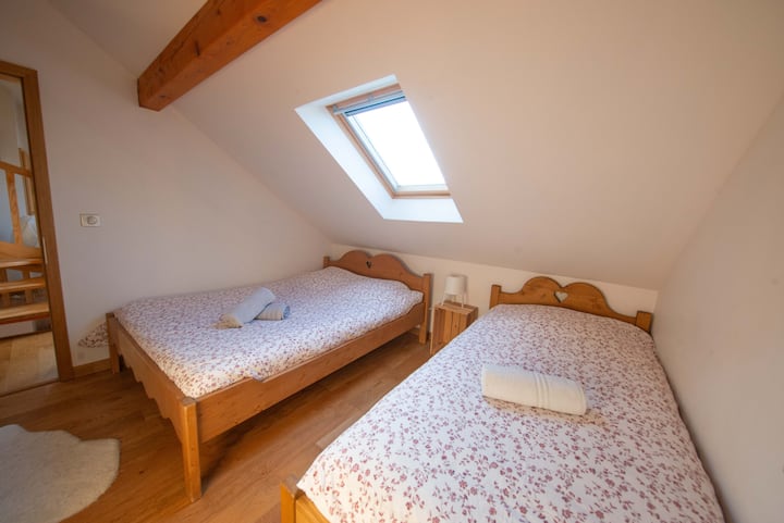 Topla soba s bračnim krevetom i krevetom za jednu osobu, idealna za boravak s obitelji ili prijateljima. Prozor koji se otvara prema kosom stropu propušta meko prirodno svjetlo, stvarajući umirujuću i autentičnu atmosferu. 