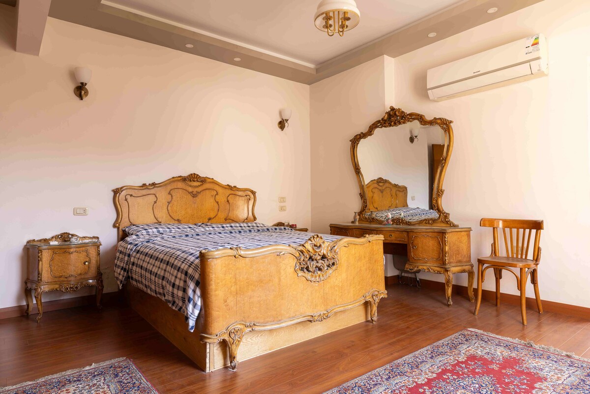 Მომხიბლავი ვინტაჟური მთავარი საძინებელი ლუქს-კლასის საწოლითა და ფართო ფანჯრით, რომლიდანაც ლამაზი ღია ხედი იშლება