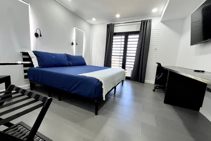 Chumba cha kulala cha msingi chenye nafasi kubwa chenye kitanda kinachoweza kurekebishwa kwa ajili ya starehe. Kituo cha kazi pia kinapatikana 