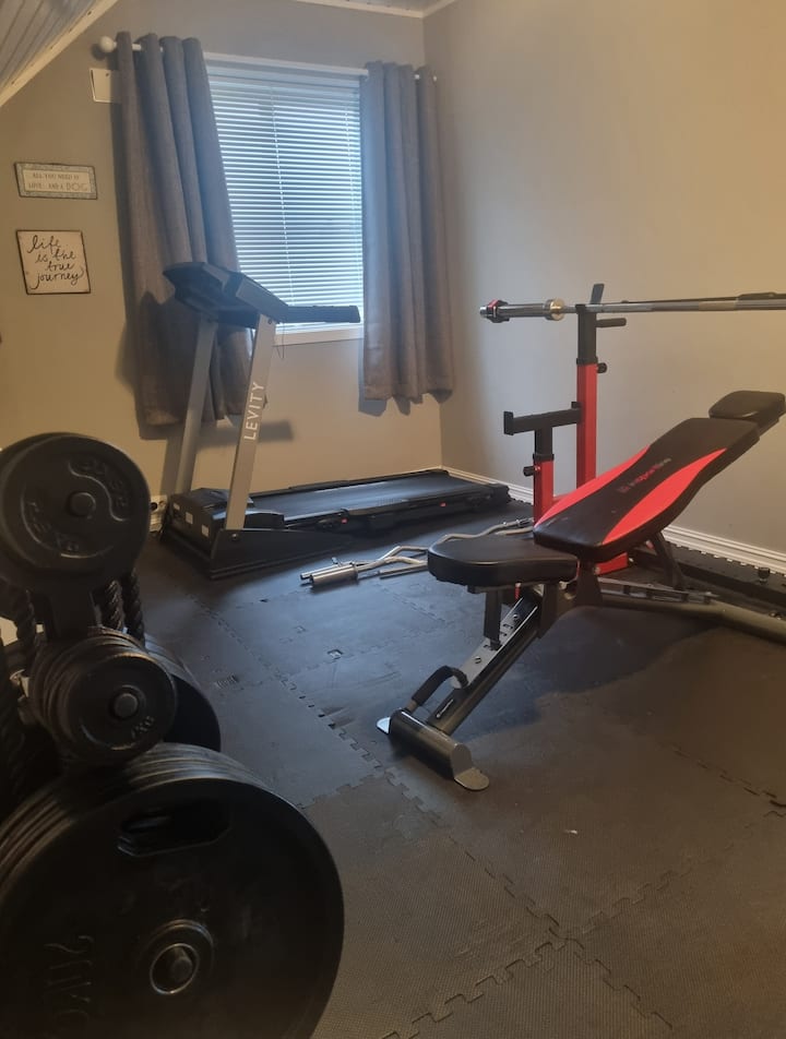 Gimnasio con cinta de correr y electrodomésticos para press de banca, sentadillas, carreras de campo y salsas. Aquí se ha colocado una cama individual para un posible quinto huésped.