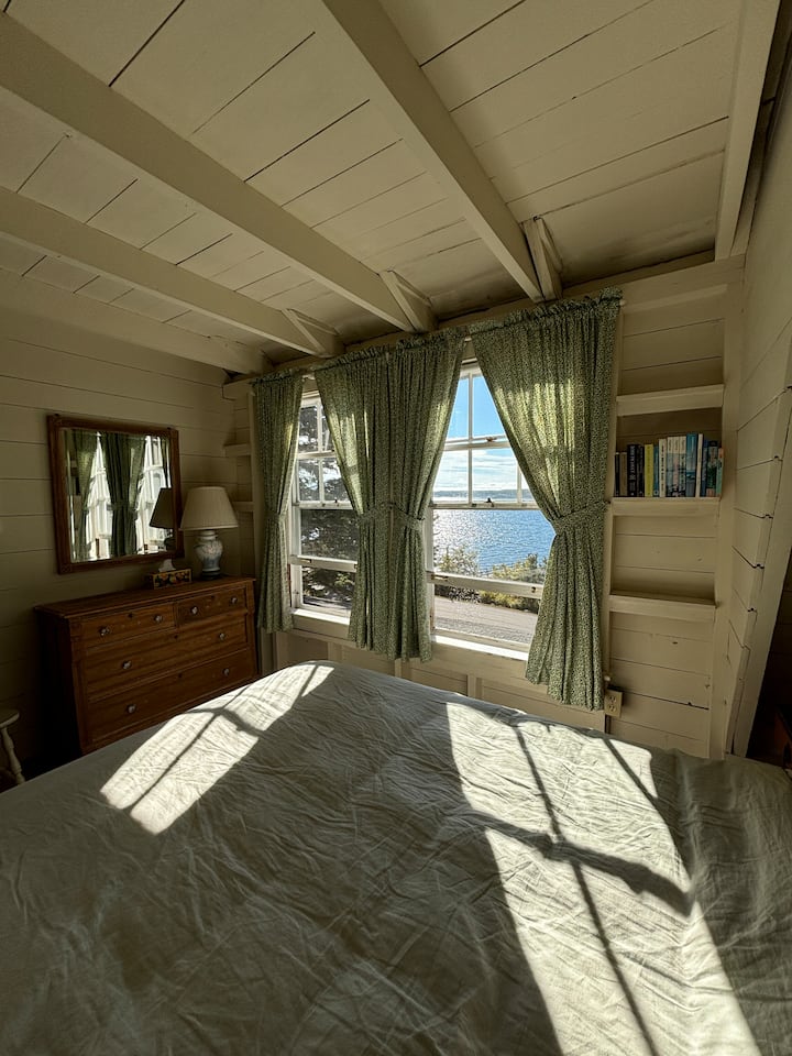 Vakna upp i detta lugna gröna sovrum på andra våningen på husets framsida, där soliga fönster erbjuder vacker havsutsikt. Somna till det lugnande ljudet av vågorna, vilket skapar den perfekta fridfulla tillflyktsorten vid havet.