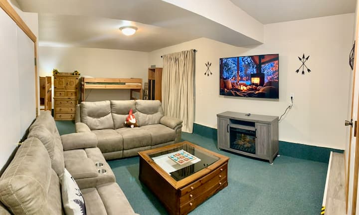 חדר למטה עם 3 מיטות קומתיים ומיטה מלאה אחת. ספה אחת ומושב אהבה אחד.