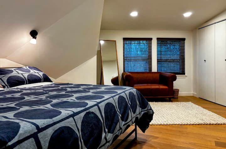 الراحة الواسعة: توفر غرفة النوم الرئيسية مساحة واسعة وسرير كينج فاخر ولمسات مدروسة مثل كرسي بذراعين من الجلد ومرآة كاملة الطول. استمتع بالهندسة المعمارية الفريدة والأجواء الهادئة لهذا المنتجع الجذاب.