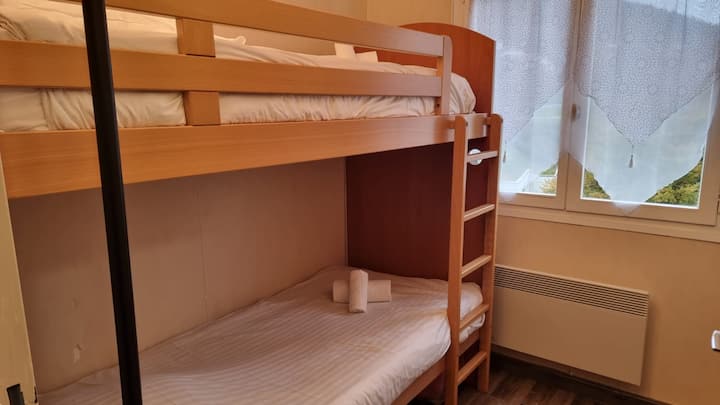 เตียงไม้สองชั้นที่อบอุ่นเหมาะสำหรับการเข้าพักสำหรับครอบครัวหรือกลุ่มเพื่อน หน้าต่างเปิดรับแสงธรรมชาติเพิ่มความนุ่มนวลให้กับที่พักที่อบอุ่นนี้