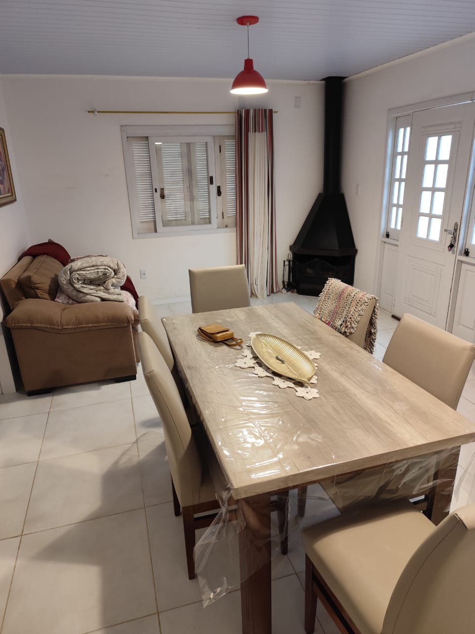 A dining area is present with a wooden table surrounded by four chairs. Natural light enters through a window, highlighting a cozy corner with a couch and a knit blanket. A fireplace adds to the warmth of the room, complemented by soft lighting.