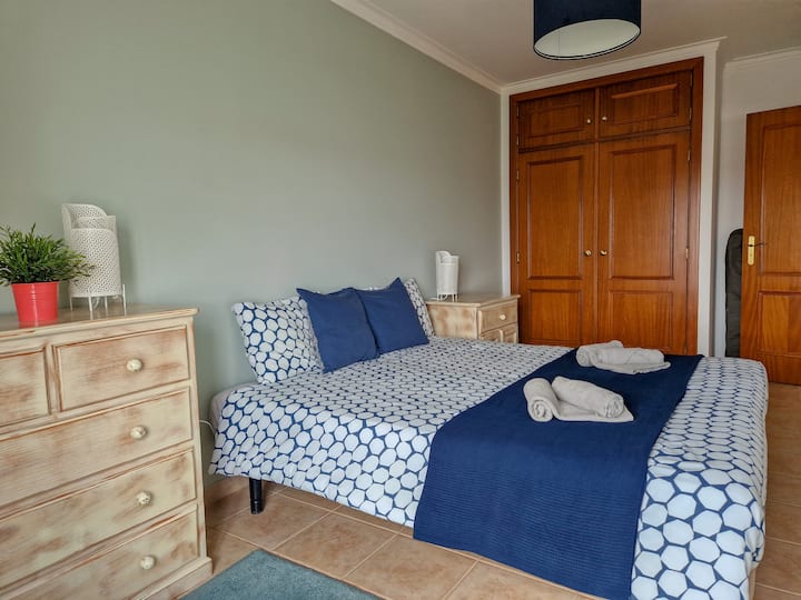 Quarto amplo com canto de leitura, roupeiro e acesso à varanda.