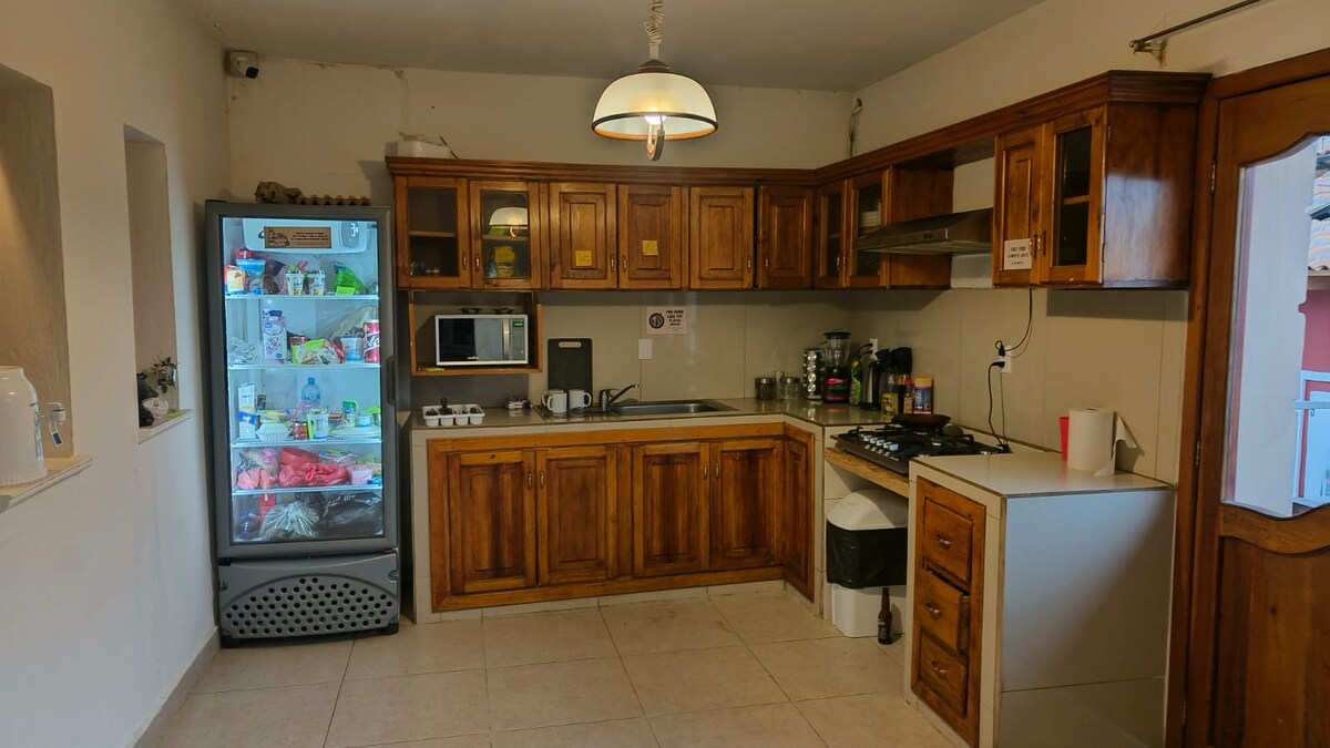 The kitchen is equipped with wooden cabinets, a microwave, and a stovetop. A refrigerator with glass doors showcases various items inside. A sink is conveniently situated near the preparation area, with ample counter space available for meal preparation.