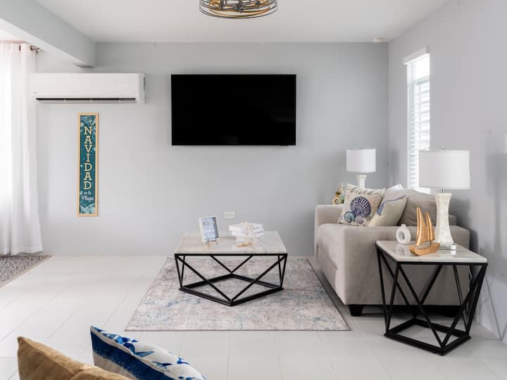 Sala con aire acondicionado, con TV de65pulgadas y un sofá tamaño queen.
