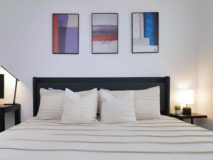 Dormitorio elegante y sofisticado con una cama cómoda, sábanas suaves y una selección seleccionada de obras de arte. La paleta de colores neutros y la decoración moderna crean un espacio elegante y sofisticado.
