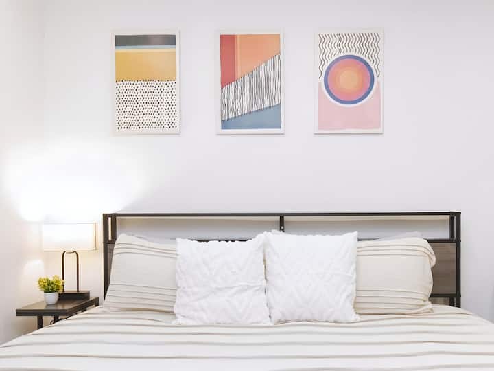 Un dormitorio sereno y elegante con una cama cómoda, sábanas suaves y una selección seleccionada de obras de arte. La paleta de colores neutros y la decoración minimalista crean un ambiente tranquilo y relajado.
