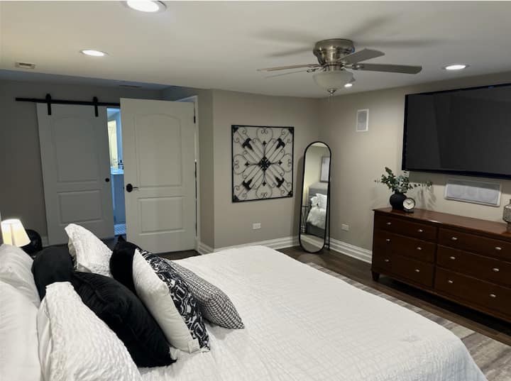 {MASTER BEDROOM} Refresh in the master bedroom with a plush king bed, 65" smart TV, dresser, and closet. The ensuite bathroom features a relaxing soaking tub and a stand-up shower for ultimate comfort.