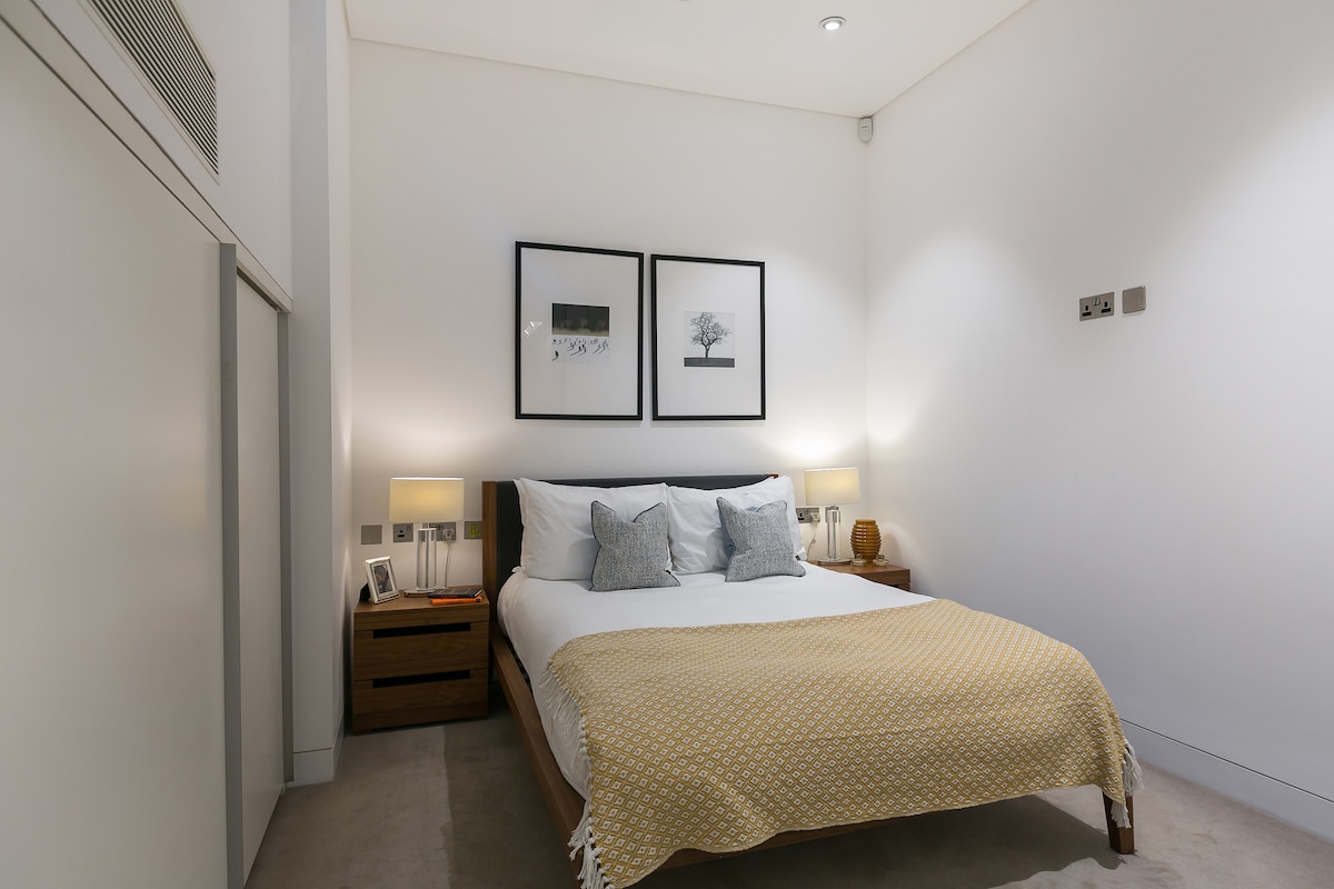 - Stylish and serene bedroom featuring a queen bed with fluffy pillows and soft throw
- Symmetrical nightstands and ambient lighting create a calm, cozy vibe
- Clean lines, plenty of space, and peaceful décor make this the perfect rest zone