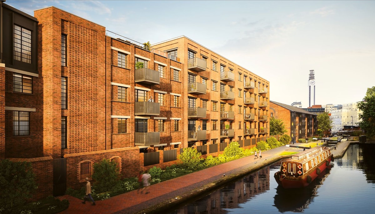 The exterior of Lockside House is showcased alongside a tranquil canal, featuring red-brick architecture with multiple balconies. A narrow pathway runs beside the water, with pedestrians strolling by. A traditional narrowboat is moored nearby, adding to the scene's charm against the backdrop of a clear sky.