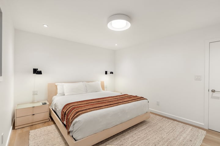 Master bedroom with a plush king bed, Smart TV, walk-in closet, and ensuite bathroom with a walk-in shower. The sauna is located at the end of the bathroom.