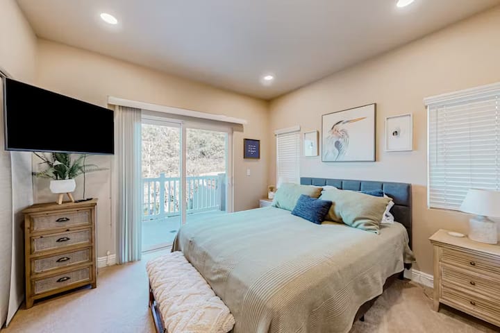 Спокойна спалня с уютно двойно легло, скрин с телевизор в ъгъла и самостоятелен балкон. Декорът на плажна тематика създава релаксираща крайбрежна атмосфера, което го прави идеалното място да се насладите на спокойни сутрини или да се отпуснете след ден на забавление край морето.