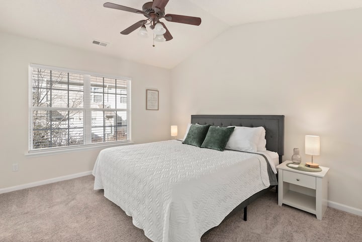 King sized bed with white linens.  Both bedrooms feature en suite full bathrooms, walk-in closets, and charging bedside lamps on both sides of the bed.