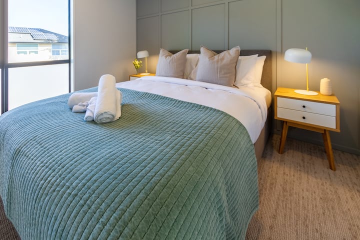 útulná a minimalistická spálňa s ostrou bielou plachtou a mäkkou zelenou prikrývkou.