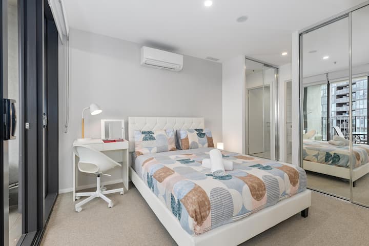 استيقظ على همسات المدينة من خلال النوافذ الكبيرة لغرفة نومنا الجذابة. السرير، يرتدي بياضات ناعمة للحصول على ليلة نوم جيدة. توفر الزاوية المريحة مع كرسي ومصباح مكانًا هادئًا للقراءة أو التأمل.