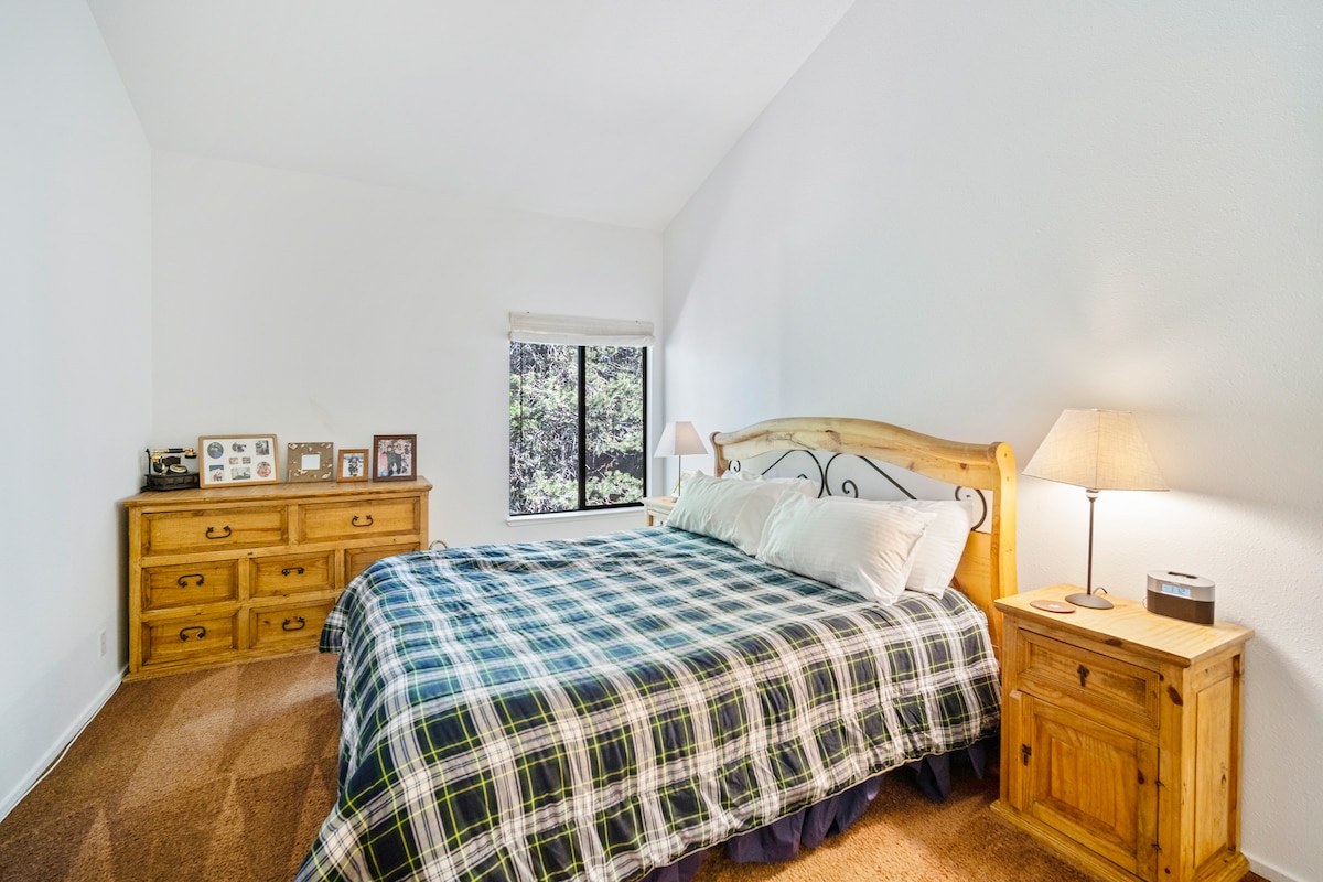 เตียงคิงไซส์ห้องนอนใหญ่เพดานสูงนี้สะอาดกว้างขวางและมีเฟอร์นิเจอร์ไม้สนที่ช่วยเติมเต็มวิวไม้อันเงียบสงบนอกหน้าต่าง