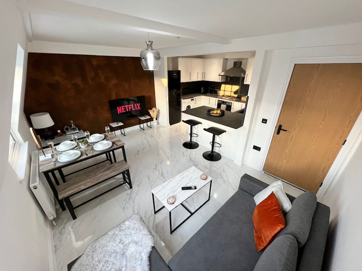 Lichte en gastvrije woonkamer met een comfortabele slaapbank, een gezellige eet-/werktafel en een flatscreen-tv voor ontspannende nachten. Snelle, betrouwbare wifi maakt het gemakkelijk om je favoriete shows te streamen of wat werk gedaan te krijgen.