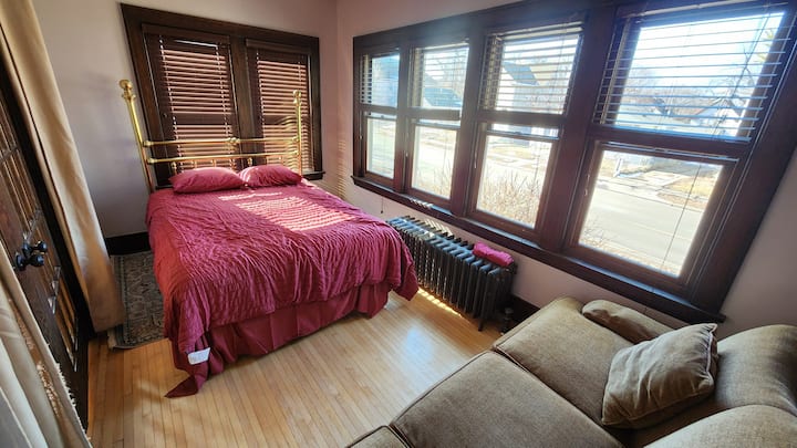 Spálňa na 1. poschodí. Žiadna skriňa. Manželská posteľ so starožitným mosadzným rámom. Stropný ventilátor. Francúzske dvere do LR. Veľký gauč na dodatočné spanie