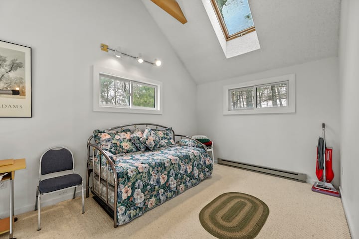 Chambre confortable avec un lit gigogne double, idéale pour des arrangements de couchage flexibles ou pour les jeunes invités, baignée de lumière naturelle provenant du puits de lumière et des fenêtres.