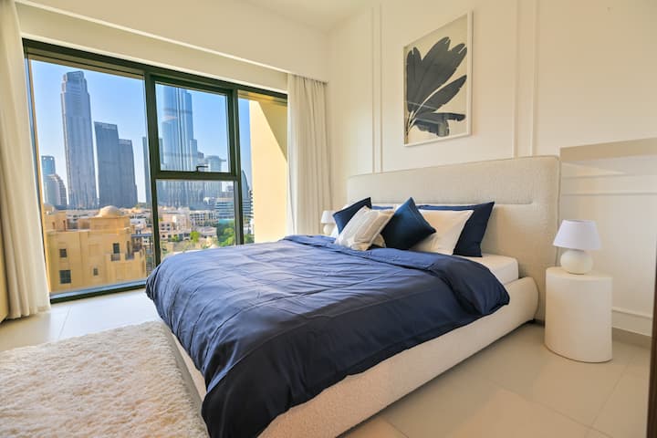 Chumba cha kulala chenye mwangaza na cha kuvutia chenye kitanda cha starehe, mapambo ya kifahari na mwonekano kamili wa Burj Khalifa, kinachotoa uzoefu wa utulivu na wa kifahari.