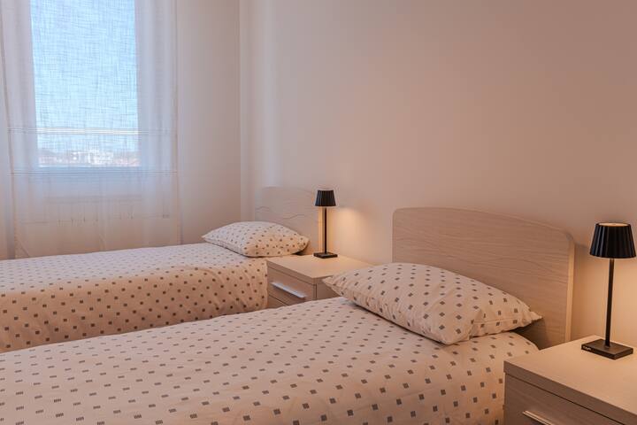 חדר עם שתי מיטות יחיד נוחות וארון בגדים מרווח למזוודות.