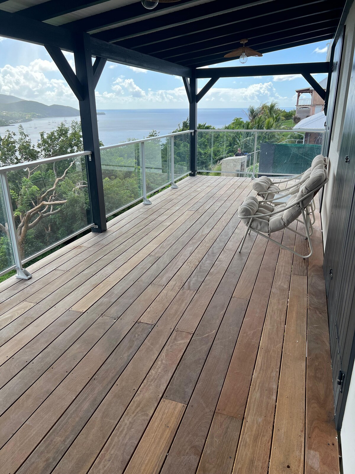 An outdoor terrace is showcased, featuring wooden flooring and a transparent railing overlooking a scenic view of the surroundings. A comfortable seating area is present, positioned to take advantage of the expansive view and natural light.