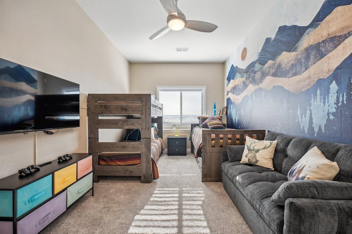 Quarto 3 com três camas de solteiro.  O Grey Futon também puxa para outra área de dormir de tamanho infantil.  Livros infantis, lâmpada de lava, TV e sistema de jogos retrô.