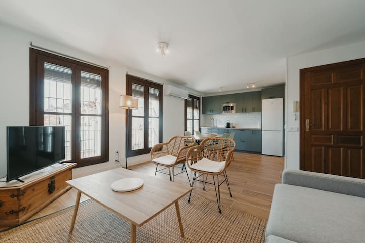 Salón con TV y ventanas de madera: cortinas opacas para dormir a oscuras.