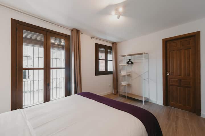 Dormitorio 1: cama de matrimonio, cortinas opacas y ventanas al casco antiguo.