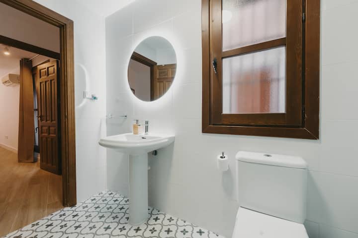 Baño completo 1: lavabo, espejo iluminado y ventana exterior.