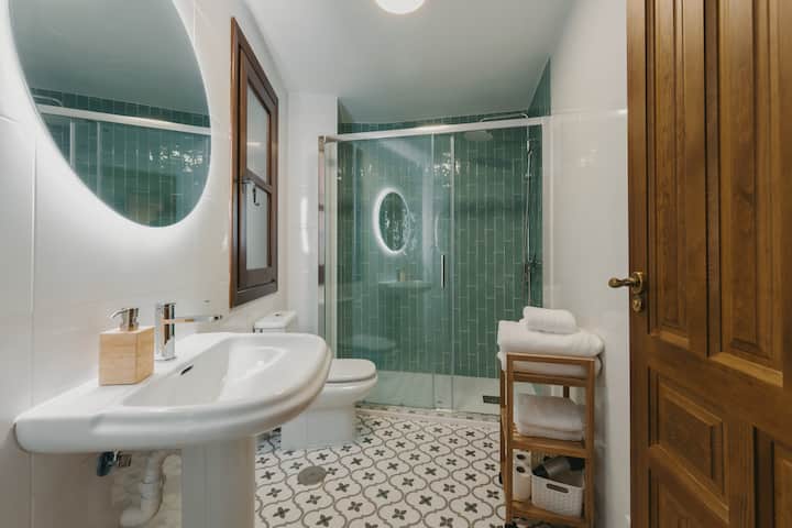 Baño completo 1: azulejo verde, ducha amplia y amenities de cortesía.