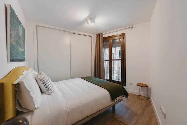 Dormitorio 2 con cama de matrimonio y vistas al entorno histórico de Toledo.