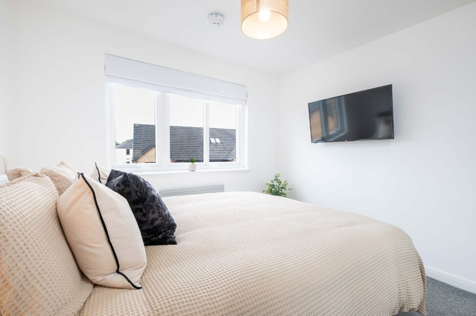 Светла и елегантна спална соба, со удобен двоен кревет и телевизор.