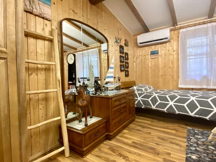 V spálni sú rôzne drevené dekorácie a starožitný príborník so zrkadlom.