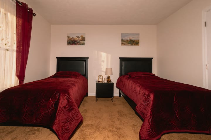 Camera bordeaux con due letti singoli, armadio e decorazioni e colori rilassanti.