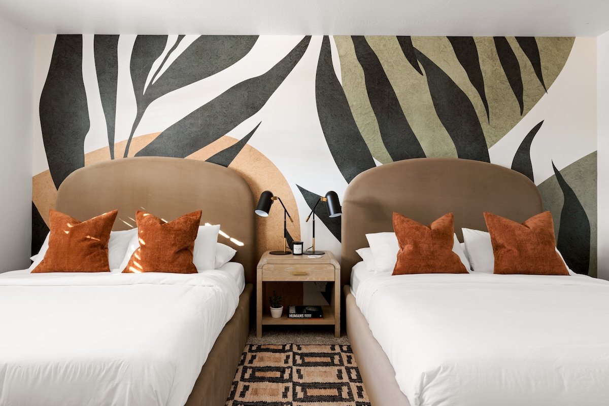 Este espacioso dormitorio cuenta con dos camas tamaño queen, perfectas para familias o amigos que viajan juntos. También incluye un espacio de trabajo con escritorio, un televisor de pantalla plana para entretenimiento y un baño privado adjunto para mayor comodidad.