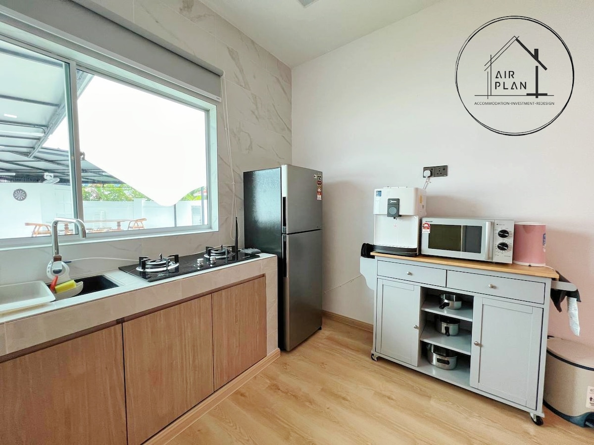 A well-equipped kitchen area is presented, showcasing a large window that allows natural light. The space features modern appliances, including a stainless steel refrigerator, a gas stove with two burners, and a microwave. A compact storage unit is visible, offering additional countertop space.