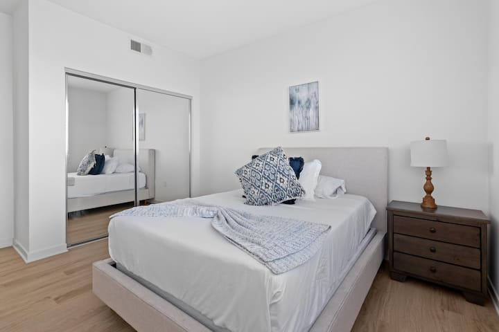 היכנסו לחדר שינה מואר ומזמין עם מיטת קווין סייז נוחה, עיצוב אלגנטי, דלת ארון הזזה עם מראה ומבטא עץ חם. המקום המושלם להירגע  #QueenBedComfort