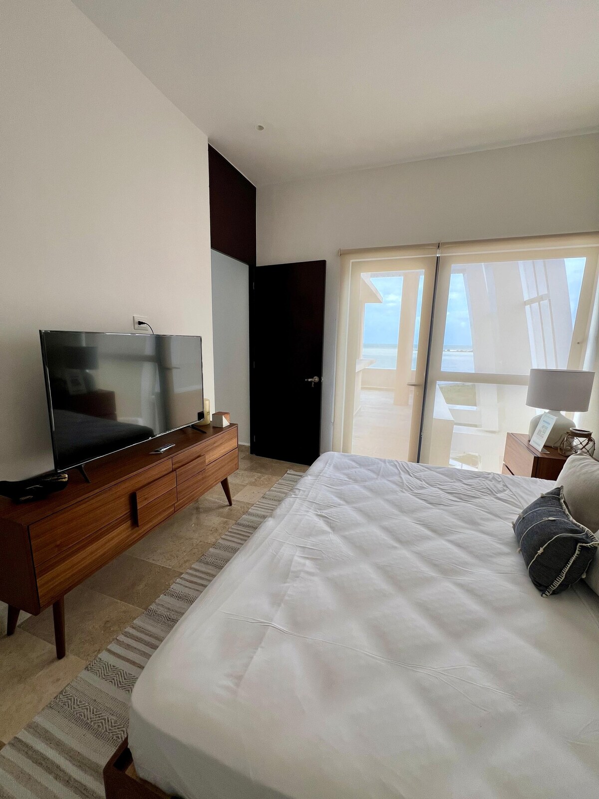 غرفة مجهزة بسرير بمقاس كبير وتلفزيون وحمام خاص ومخرج مع شرفة تطل على البحر.